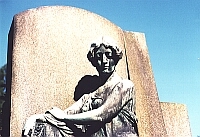 
     statue of a woman    
   in front of a tombstone   
